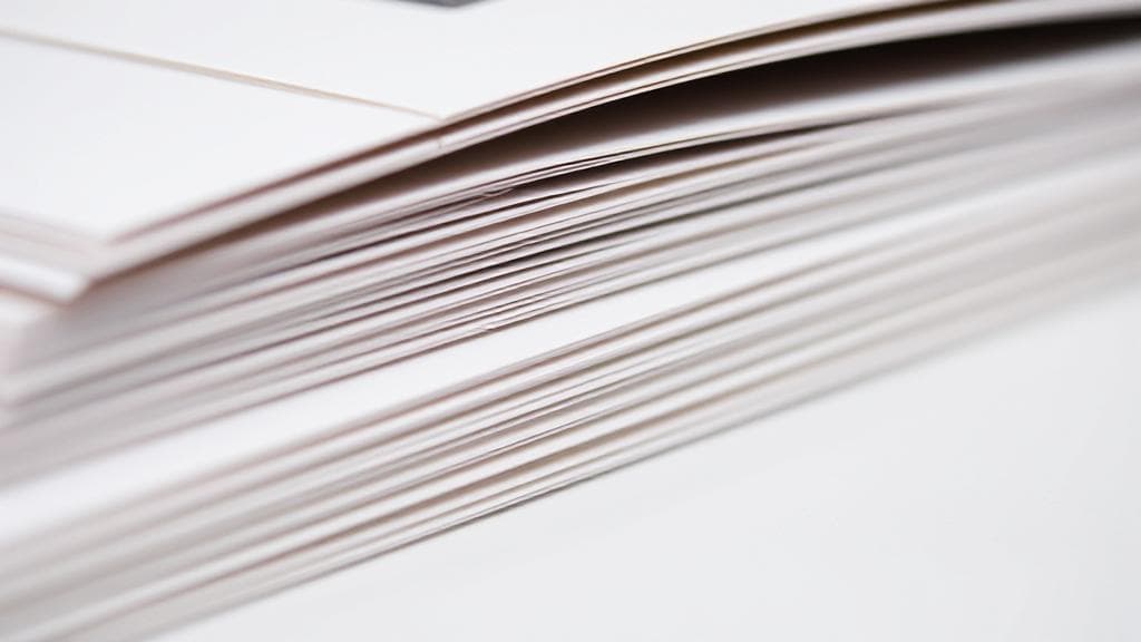 A close-up image of a neatly stacked set of saddle-stitched booklets, showcasing the precision and elegance of the binding technique.